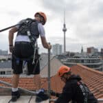Zwei Mitarbeiter auf Gerüst über den Dächern