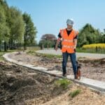 Mann bei Vermessungsarbeiten beim Straßenbau.